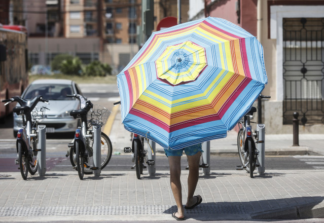 Archivo - Un hombre con una sombrilla cerca de la Playa de la Malvarrosa, en Valencia