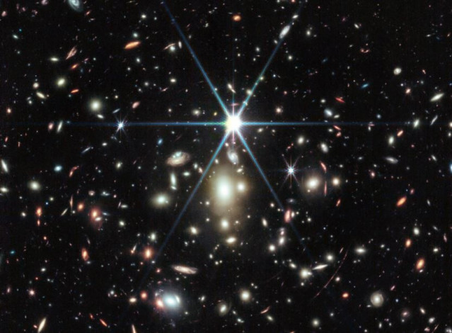Esta imagen del Webb de un cúmulo de galaxias masivo llamado WHL0137-08 contiene la galaxia más aumentada conocida en los primeros mil millones de años del universo: el Arco del Amanecer, y dentro de esa galaxia, la estrella más distante jamás detectada.