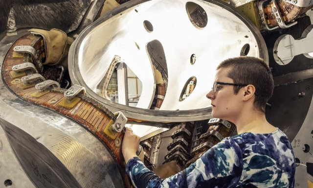 La estudiante de posgrado Alexandra LeViness junto a parte de un estelarator, un dispositivo de fusión retorcido diseñado para confinar plasma ultracaliente para facilitar las reacciones de fusión.