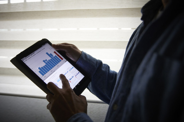 Archivo - Un hombre sujeta una tablet con un gráfico