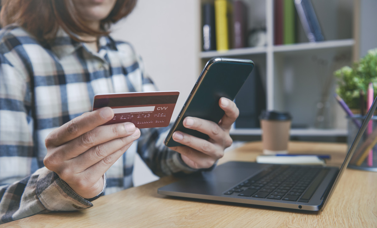 Mujer joven tenencia tarjeta credito utilizar telefono inteligente compra onl