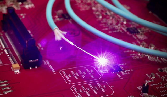 Luz que viaja a través de una fibra óptica situada encima de una placa de circuito electrónico convencional.