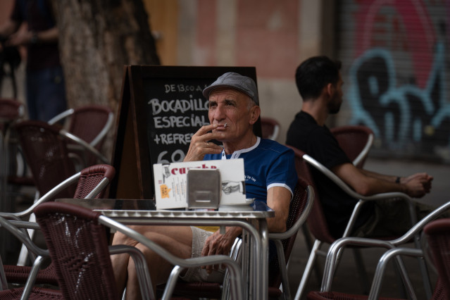 Archivo - Un hombre fuma sentado en la mesa de una terraza que una nueva normativa convertirá en espacio libre de humo por el Govern, en plaza de la Vila de Gràcia, a 23 de septiembre de 2022, en Barcelona, Catalunya (España). La nueva normativa consiste