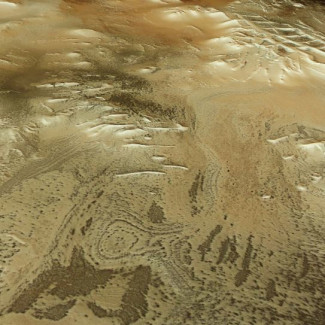 Esta imagen rectangular muestra parte de la superficie marciana como si el espectador estuviera mirando hacia abajo y a través del paisaje, con el suelo irregular y moteado apareciendo en tonos arrem