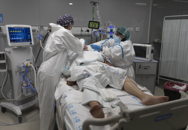 Archivo - Dos sanitarios alrededor de un paciente ingresado en la UCI del Hospital Enfermera Isabel Zendal, a 13 de enero de 2022, en Madrid (España). La incidencia acumulada a 14 días en la Comunidad de Madrid ha subido 87,35 puntos, hasta situarse en 2.