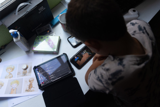 Archivo - Un niño usa el teléfono móvil y una tablet, a 18 de octubre de 2023, en Madrid (España). Según la Vanguardia, en España se estima que el 21% de los adolescentes es adicto a la red y casi la mitad reconoce que tiene 'un contacto activo' cada 15 m