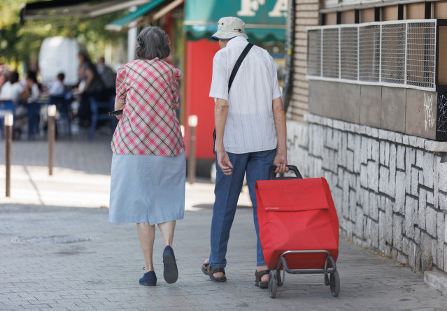 Archivo - Una pareja mayor caminan con un carro de la compra, a 24 de julio de 2023, en Madrid (España). La población mayor de 64 años en España está por encima del 20% del total y supera al grupo de personas menor de 20 años, lo que produce un 'creciente
