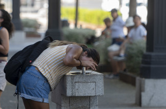 Archivo - Una mujer bebe agua de una fuente, a 21 de agosto de 2023, en Madrid (España). Los termómetros suben hoy en uno de los 'días álgidos' de una nueva ola de calor, la cuarta que se registra