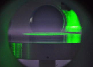 Una vista dentro de la cámara de vacío del laboratorio, donde las partículas coloidales están suspendidas en un disco plano, iluminado por la luz verde de un láser, para estudiar el plasma polvor