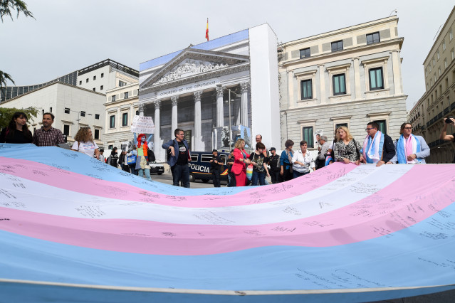 Archivo - Varias personas sostienen la bandera trans que la Federación Estatal de Lesbianas, Gais, Trans, Bisexuales, Intersexuales y más (Flegtbi+), Chrysallis y Fundación Triángulo han llevado al Congreso de los Diputados, a 27 de octubre de 2022, en Ma
