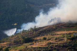 Un helicóptero colabora en las labores de extinción del incendio, a 19 de agosto de 2025, en Quiroga, Lugo, Galicia (España). El fuego amenaza la sierra de O Courel en su avance desde la localidad 