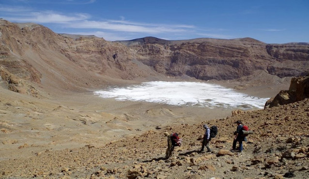 Descenso al subcráter Era Kohor, dentro de la caldera de la cima de Emi Koussi, la montaña más alta del Sahara, a 3415 m. Se pueden observar sedimentos blanquecinos en el fondo del cráter: costras de sal de la desecación del lago.