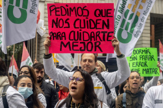 Manifestante con pancarta con lema 'Pedimos que nos cuiden para cuidarte mejor' durante la manifestación ‘Todos unidos por un objetivo común: el estatuto propio’, a 15 de noviembre de 2025, en M
