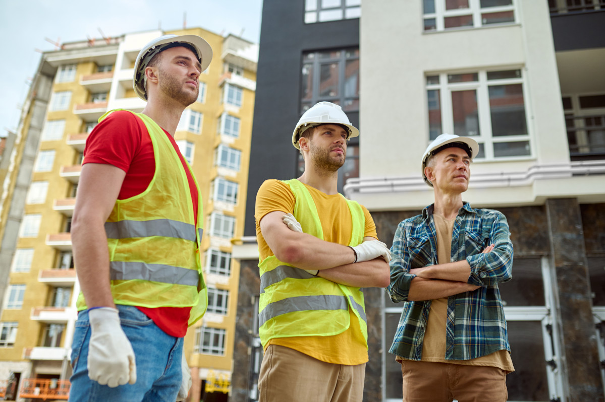 Three men looking aside construction site