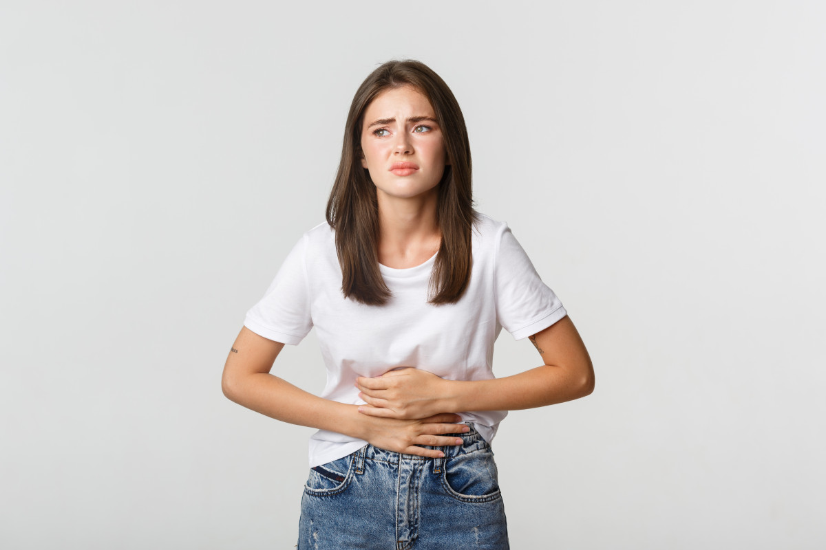 Woman having stomach ache bending with hands belly discomfort from menstrual cramps