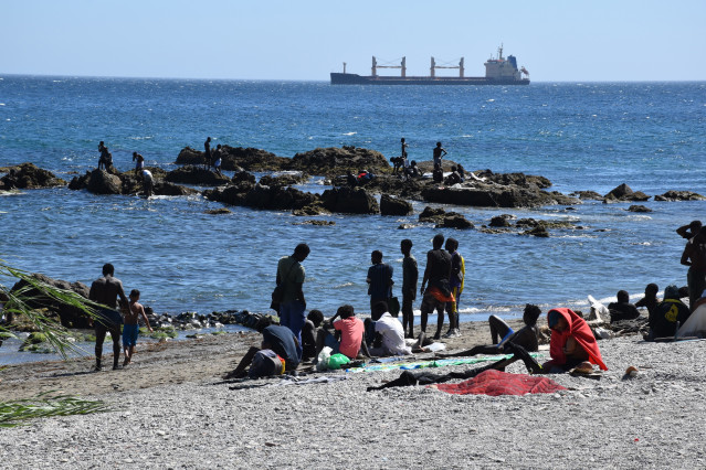 Varias personas en la playa del Trampolín, a 5 de agosto de 2026, en Ceuta (España). La Policía Nacional ha comenzado el proceso de triaje de los migrantes que permanecen en Ceuta, 'unos 2.500' según informaciones de la Delegación del Gobierno,  tras la e
