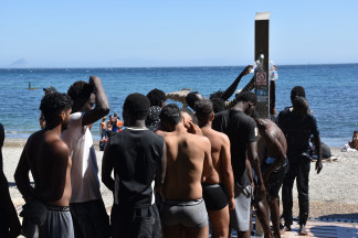 Varias personas se asean en las duchas públicas, en la playa del Trampolín, a 5 de agosto de 2026, en Ceuta (España). La Policía Nacional ha comenzado el proceso de triaje de los migrantes que per