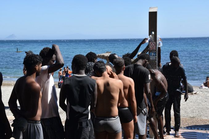Varias personas se asean en las duchas públicas, en la playa del Trampolín, a 5 de agosto de 2026, en Ceuta (España). La Policía Nacional ha comenzado el proceso de triaje de los migrantes que per