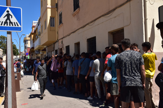 Varias personas hacen cola en un punto de atención humanitaria, a 5 de agosto de 2026, en Ceuta (España). Varias personas y agentes sociales, se han reunido en sedes y casas donde reparten comida, ropa y otros productos y dejan ducharse a las personas mig