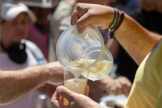 Una persona sirve un vaso de limonada durante un aperitivo vecinal por las Fiestas de San Cayetano, en la Plaza de Cascorro, a 7 de agosto de 2026, en Madrid (España). El aperitivo ha sido organizado