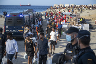 Miembros de la Cruz Roja atienden a varios inmigrantes, en la playa del Trampolín, a 20 de agosto de 2026, en Ceuta (España). El Ministerio de Defensa ha aprobado que más de un centenar de militare