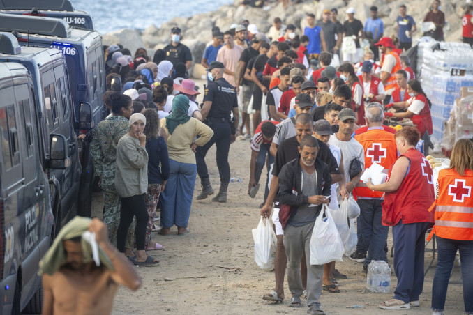 Miembros de la Cruz Roja atienden a varios inmigrantes, en la playa del Trampolín, a 20 de agosto de 2026, en Ceuta (España). El Ministerio de Defensa ha aprobado que más de un centenar de militare