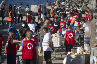 Miembros de la Cruz Roja reparten comida a los inmigrantes en una playa, a 21 de agosto de 2026, en Ceuta (España). Ceuta sigue afrontando una grave crisis humanitaria después de la histórica entra