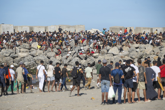 Miembros de la Cruz Roja reparten comida a los inmigrantes en una playa, a 21 de agosto de 2026, en Ceuta (España). Ceuta sigue afrontando una grave crisis humanitaria después de la histórica entrada masiva de más de 70.000 migrantes a nado por el Tarajal
