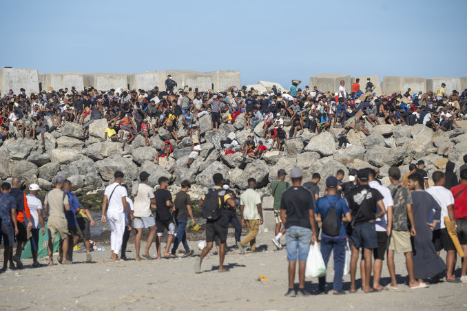 Miembros de la Cruz Roja reparten comida a los inmigrantes en una playa, a 21 de agosto de 2026, en Ceuta (España). Ceuta sigue afrontando una grave crisis humanitaria después de la histórica entra