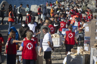 Miembros de la Cruz Roja reparten comida a los inmigrantes en una playa, a 21 de agosto de 2026, en Ceuta (España). Ceuta sigue afrontando una grave crisis humanitaria después de la histórica entra